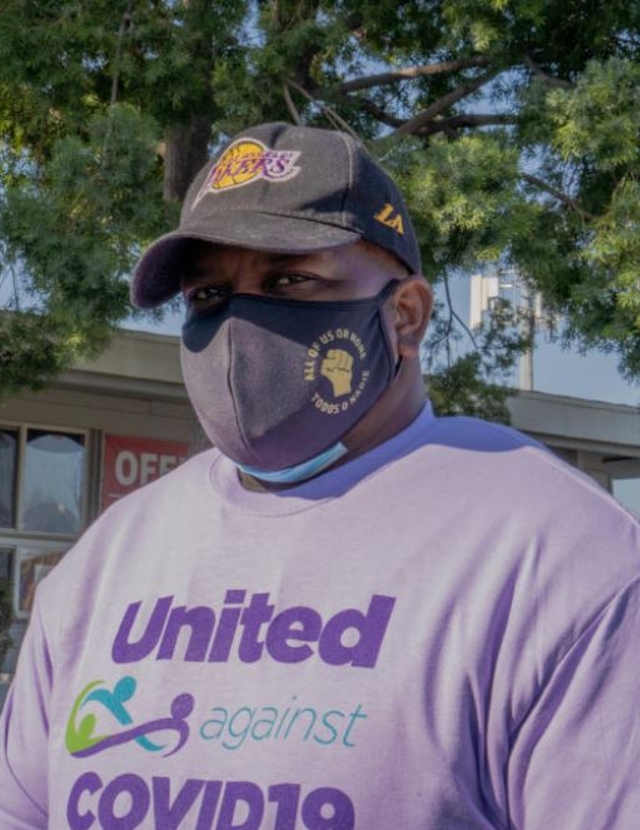 A man wearing a "United Against COVID" t-short and a medical mask