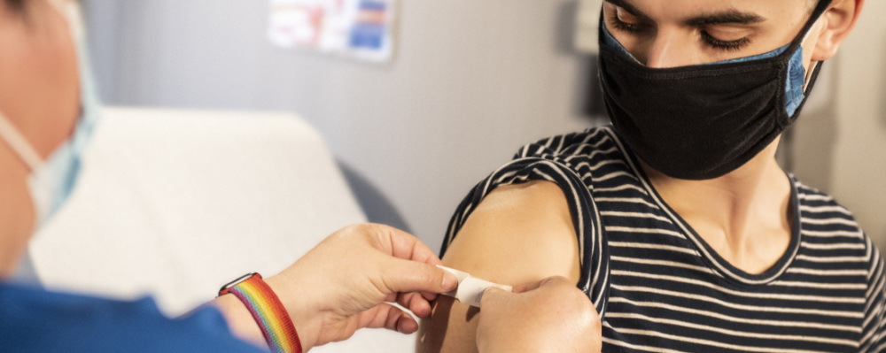 a health worker putting a band aid on a patient's arm after vaccination