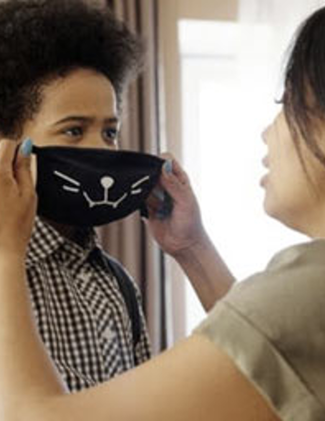 a Mom helping her child put on a medical mask