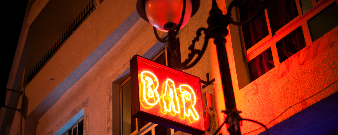 a neon street sign reading "Bar"