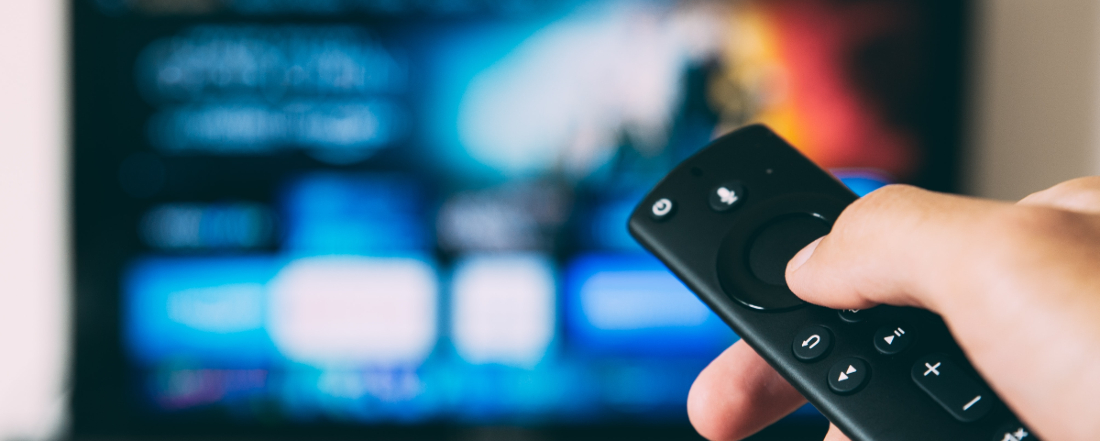 a hand holding a remote control about to change a TV channel