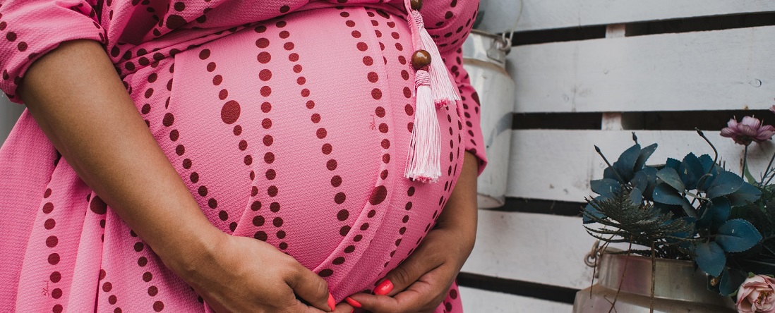 Close up of a pregnant person holding their belly