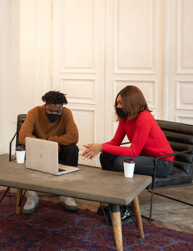 A young African American man sitting in front of a laptop with an African American woman