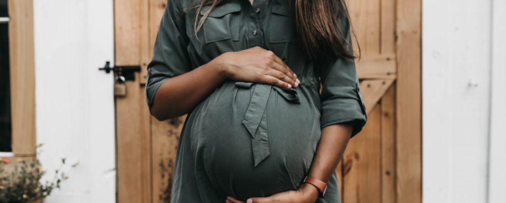 a woman holding her pregnant belly with both hands