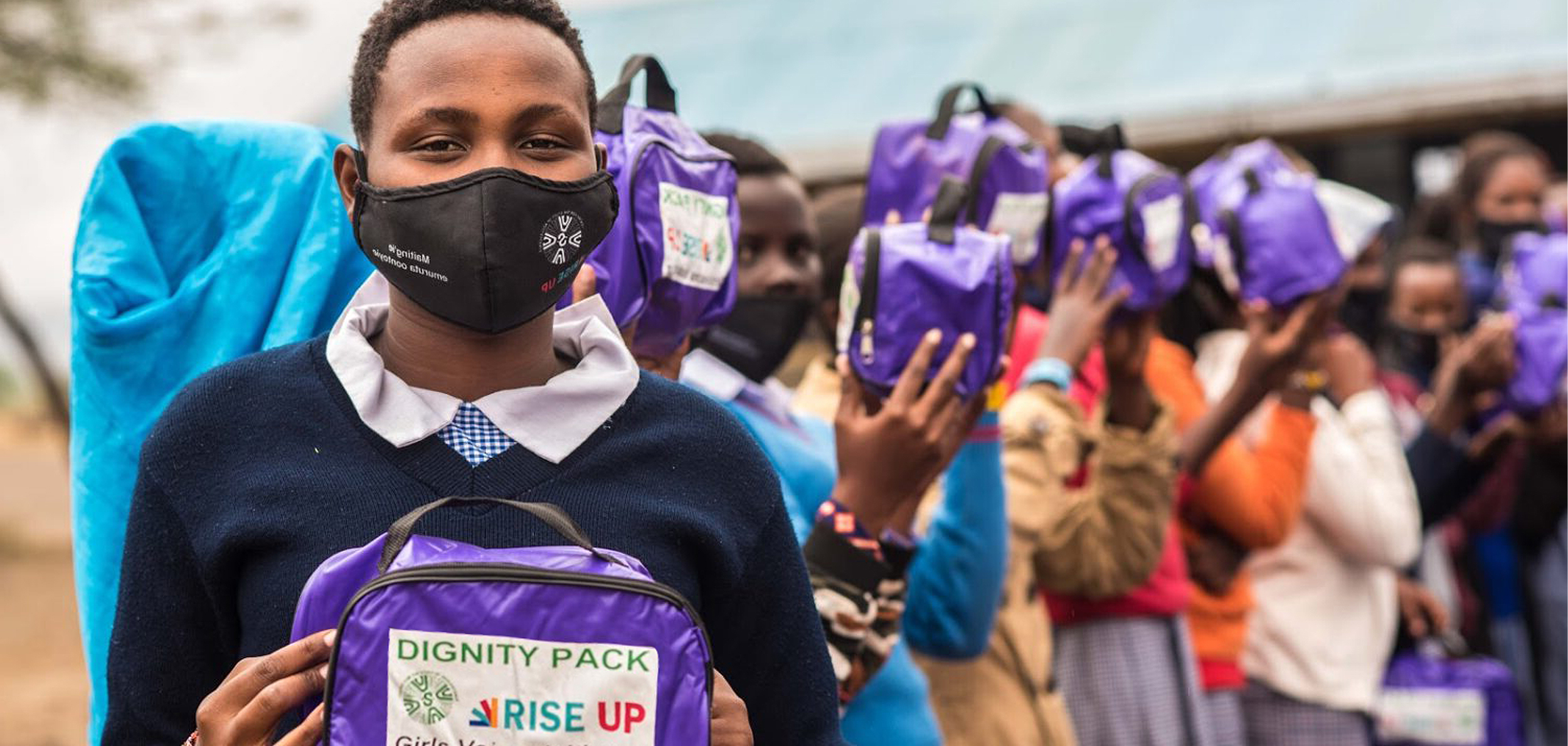 Rise Up youth leaders holding dignity packs and wearing masks