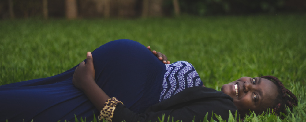 a pregnant woman lying in a field of grass