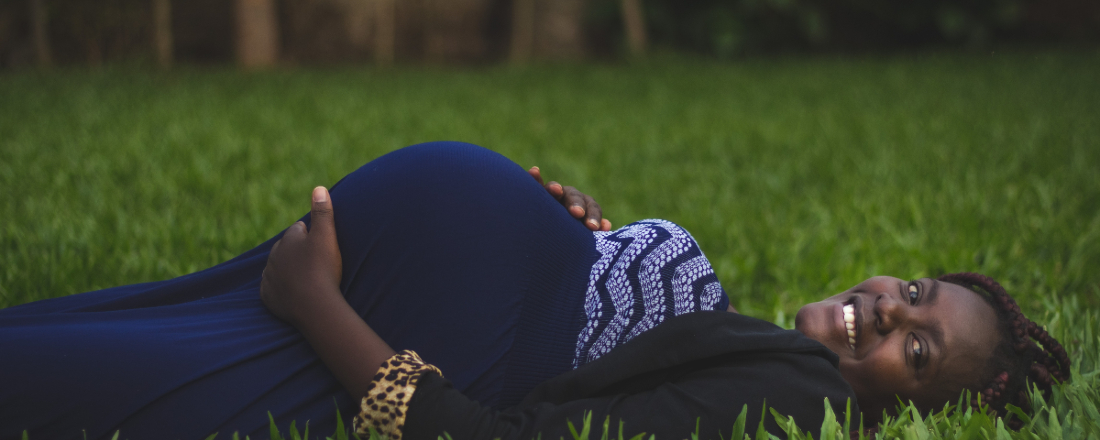 a pregnant woman lying in a field of grass