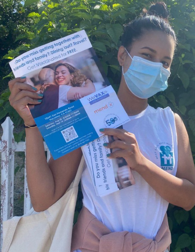 a young woman in a medical mask holding up vaccine information