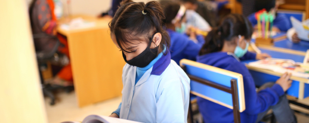a young girl in a classroom at school in a medical mask