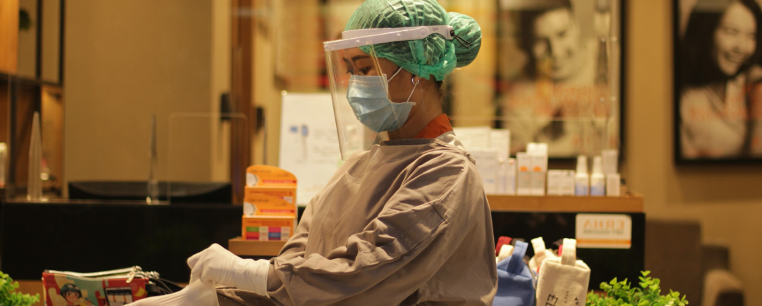 a healthcare worker in a medical mask, face shield and gown