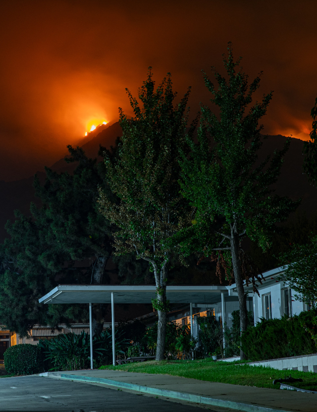 a wildfire burning behind a roadside home