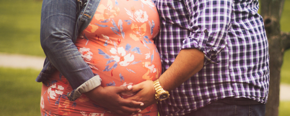 a pregnant women hugged by her partner