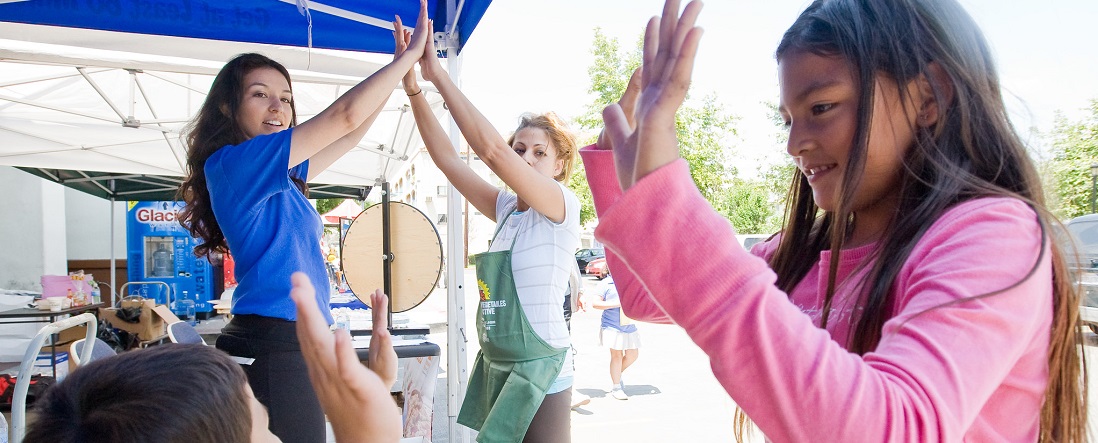 People at an outdoor booth, giving high fives