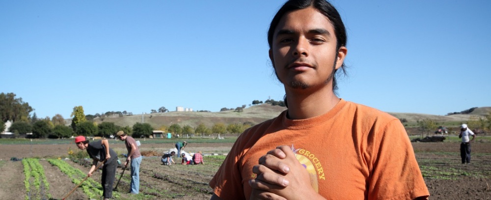 Marcelo Garzo, urban agriculture program assistant for food justice organization Peoples Grocery, shows some Oakland youth how to hoe a garden