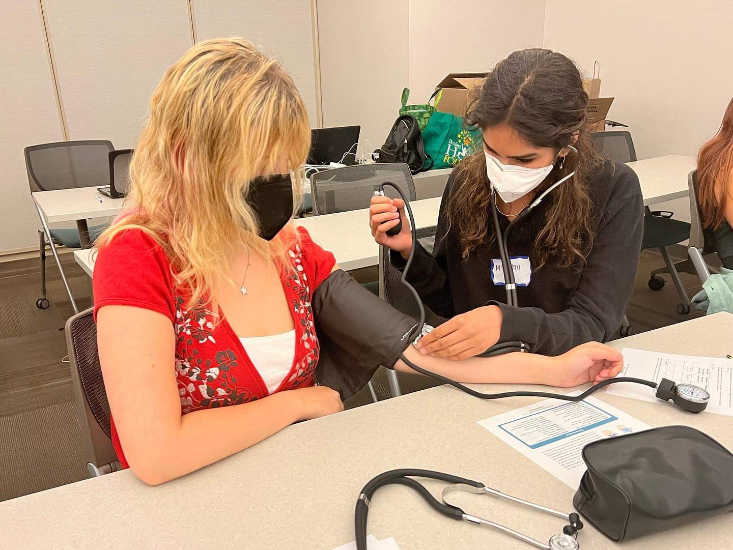 Two FACES students learning how to check blood pressures using blood pressure cuff