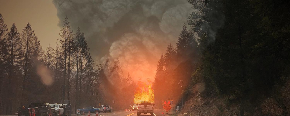 Car driving away from a wildfire in the mountains
