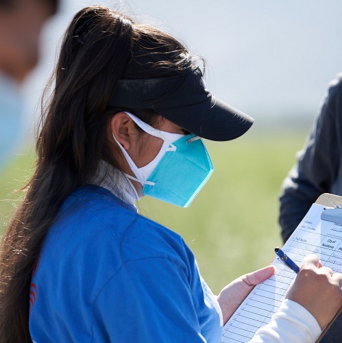 A woman wearing a mask, signing people up for vaccines
