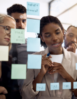 People standing in front of a glass wall with sticky notes