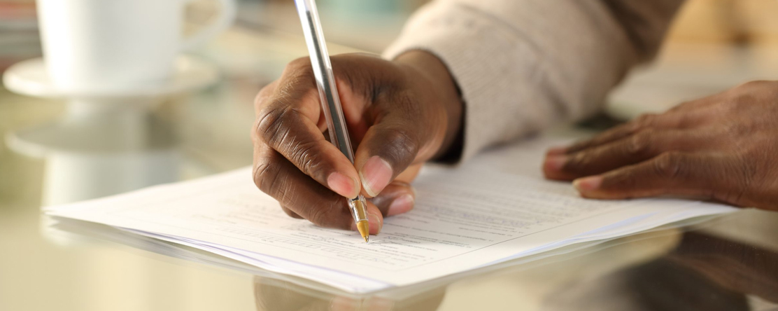 person's hand using pen to write on paper