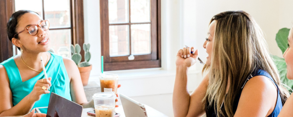 three women sitting at desk talking