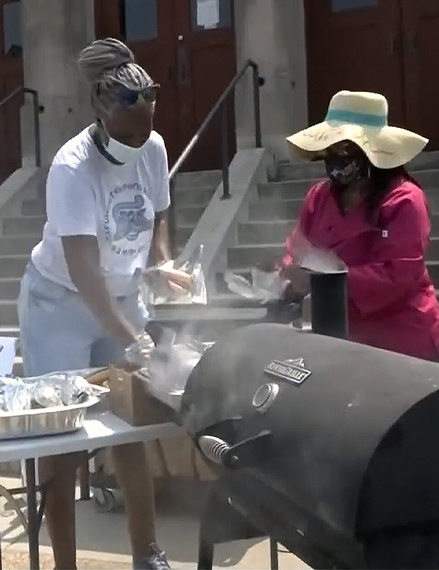 two volunteers grilling hotdogs