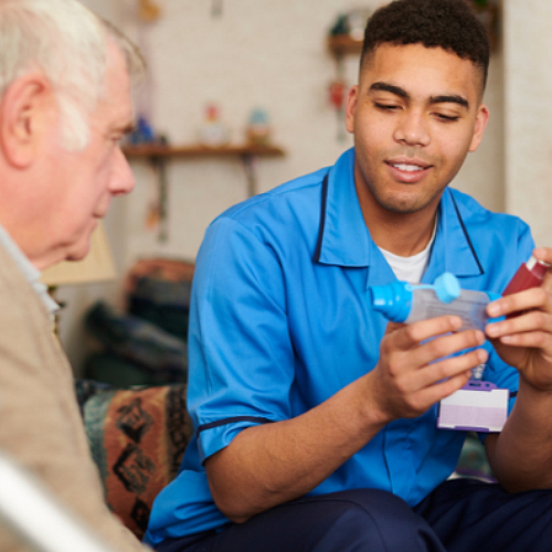 older man sitting with young man holding an inhaler at home