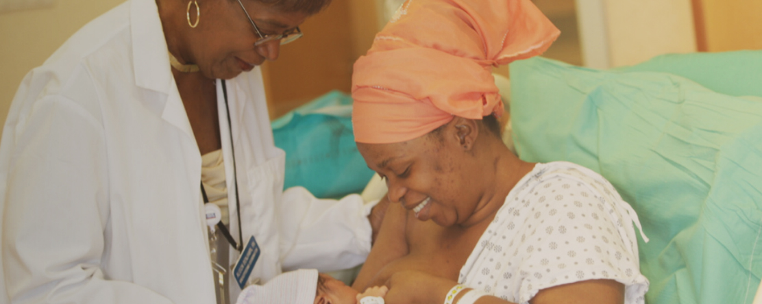 woman breastfeeding newborn baby with doctor