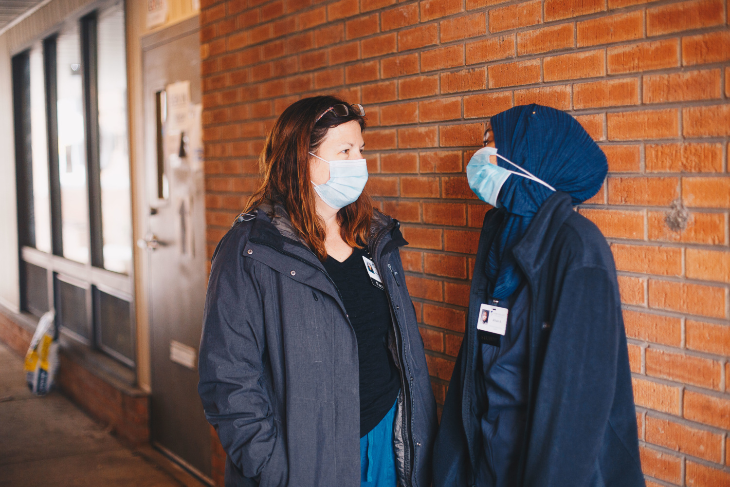 two women speaking wearing face masks