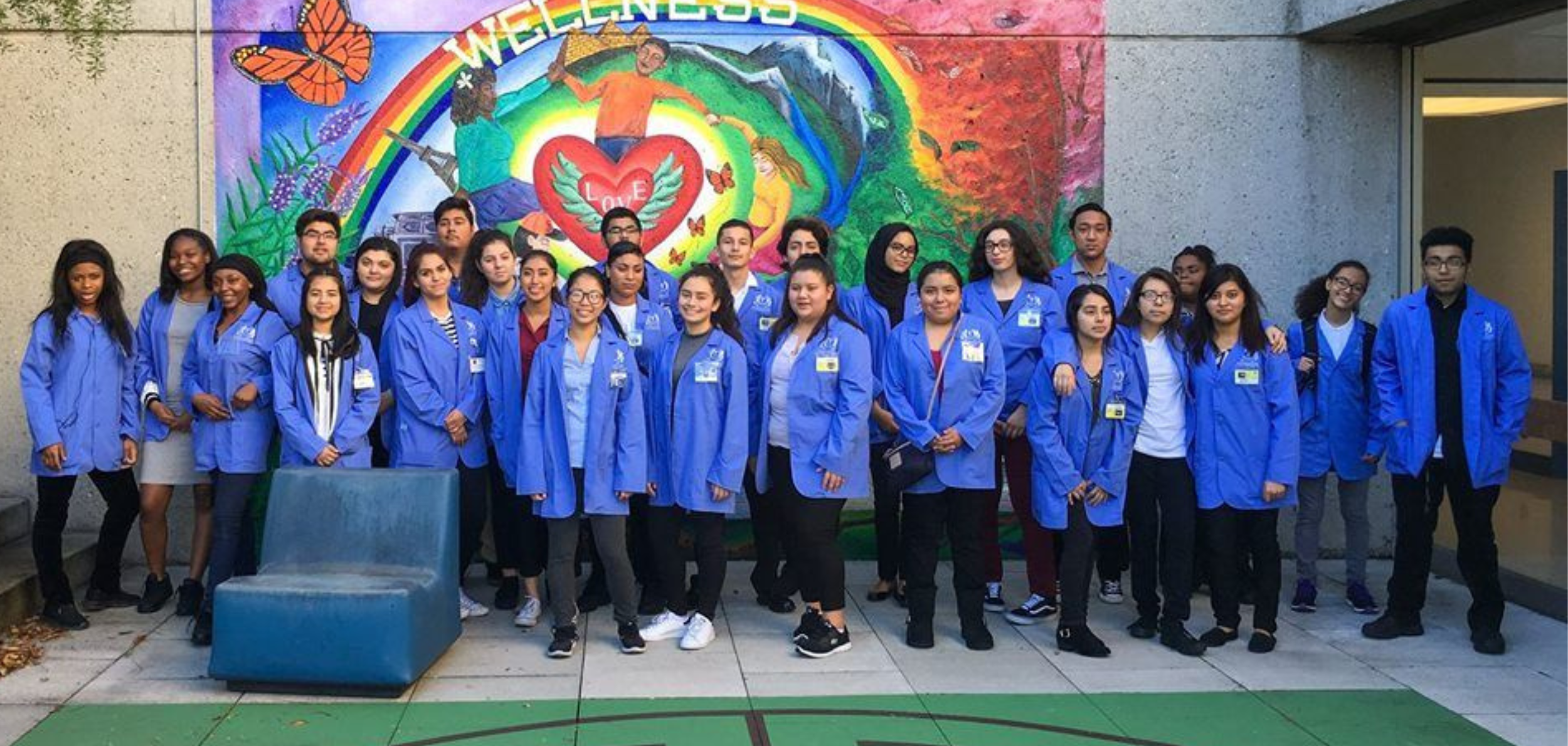 FACES for the Future students, standing in front of a mural