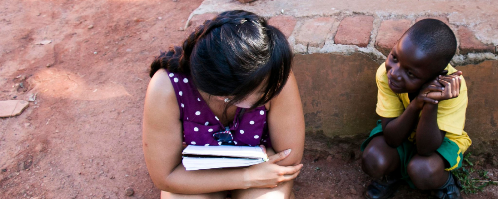 African child sitting on the ground and talking to a woman