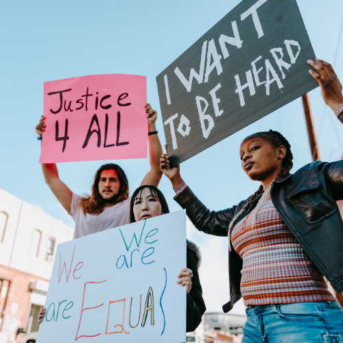 Three protestors holding signs: "Justice 4 All" "We All Are Equal" and "I Want To Be Heard"