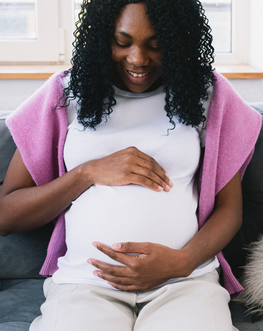 Black pregnant woman, smiling and holding her belly