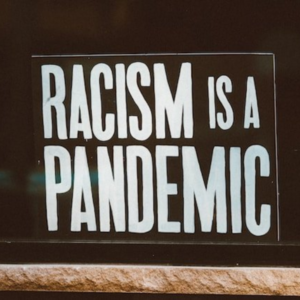 Black sign with white letters that read "Racism is a pandemic."