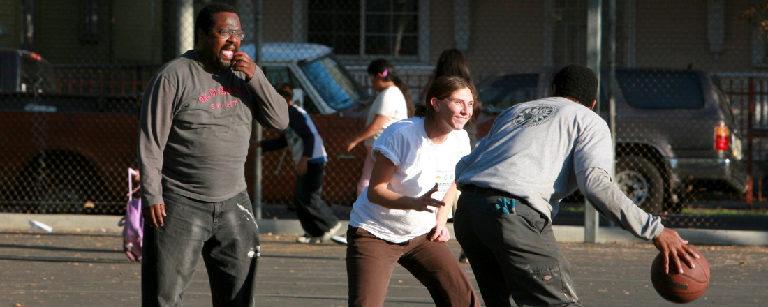 three community members playing basketball outside