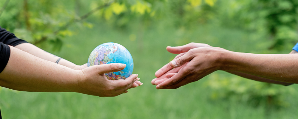 one person holding a globe and passing it to another person