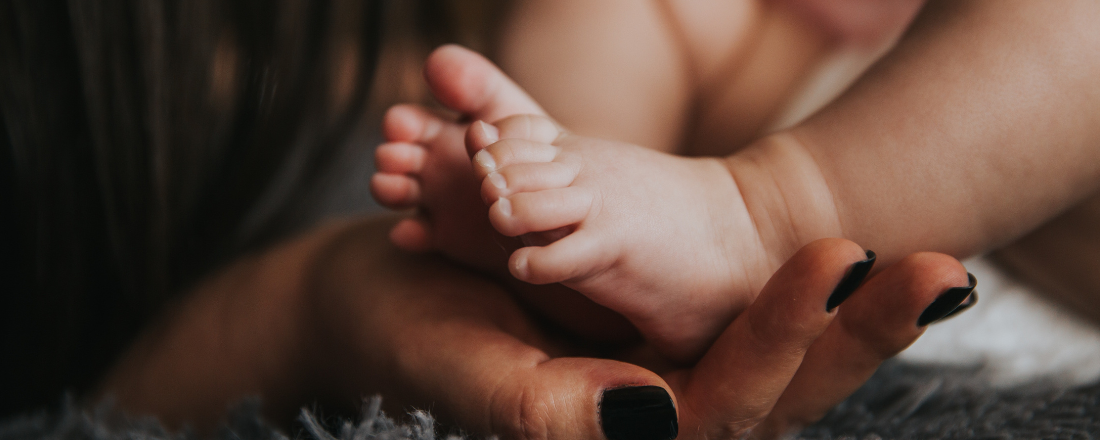 woman holding baby's foot in the palm of her hand