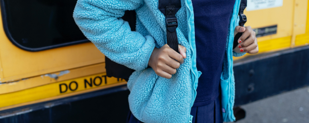 child standing near standing near a school bus