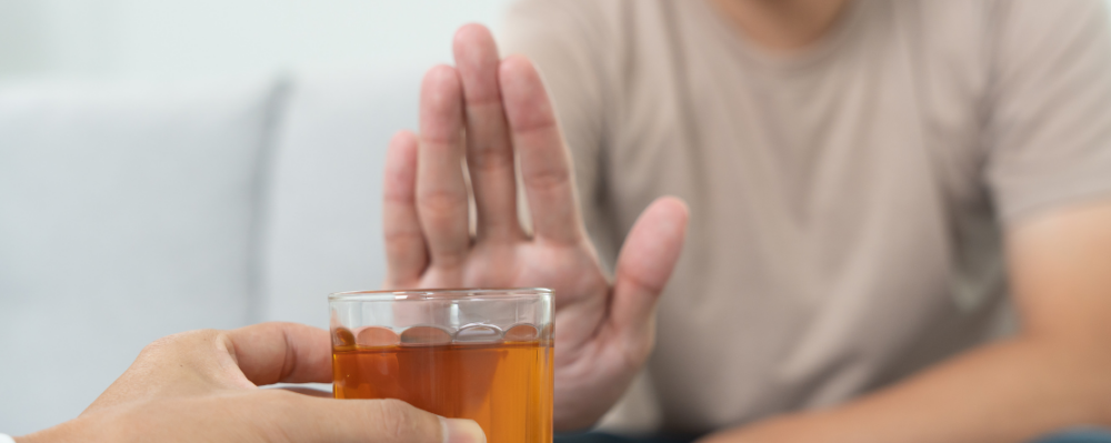 hand in front of glass of alcohol (credit: shisuka from Canva)