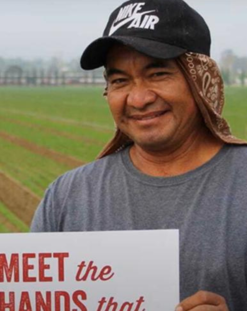 Screenshot of farmworker holding a sign, "Meet the hands that feed you"