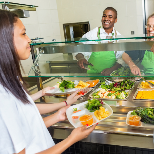 High school cafeteria workers serving healthy lunch options to students