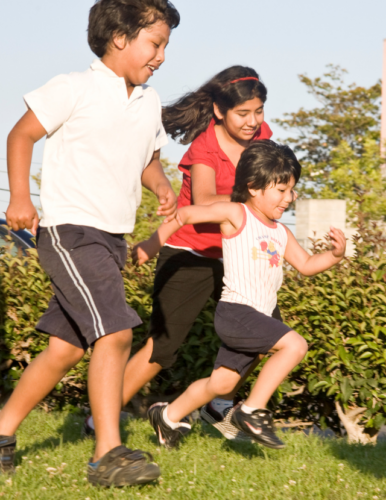 A family plays soccer on a narrow strip of grass.