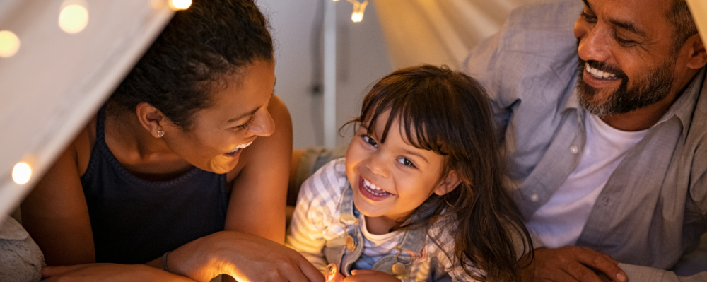 Young child with parents in a blanket fort