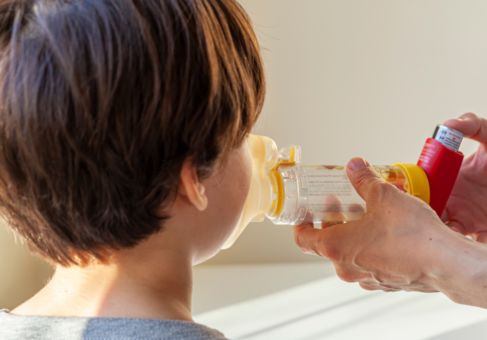 person helping child use inhaler