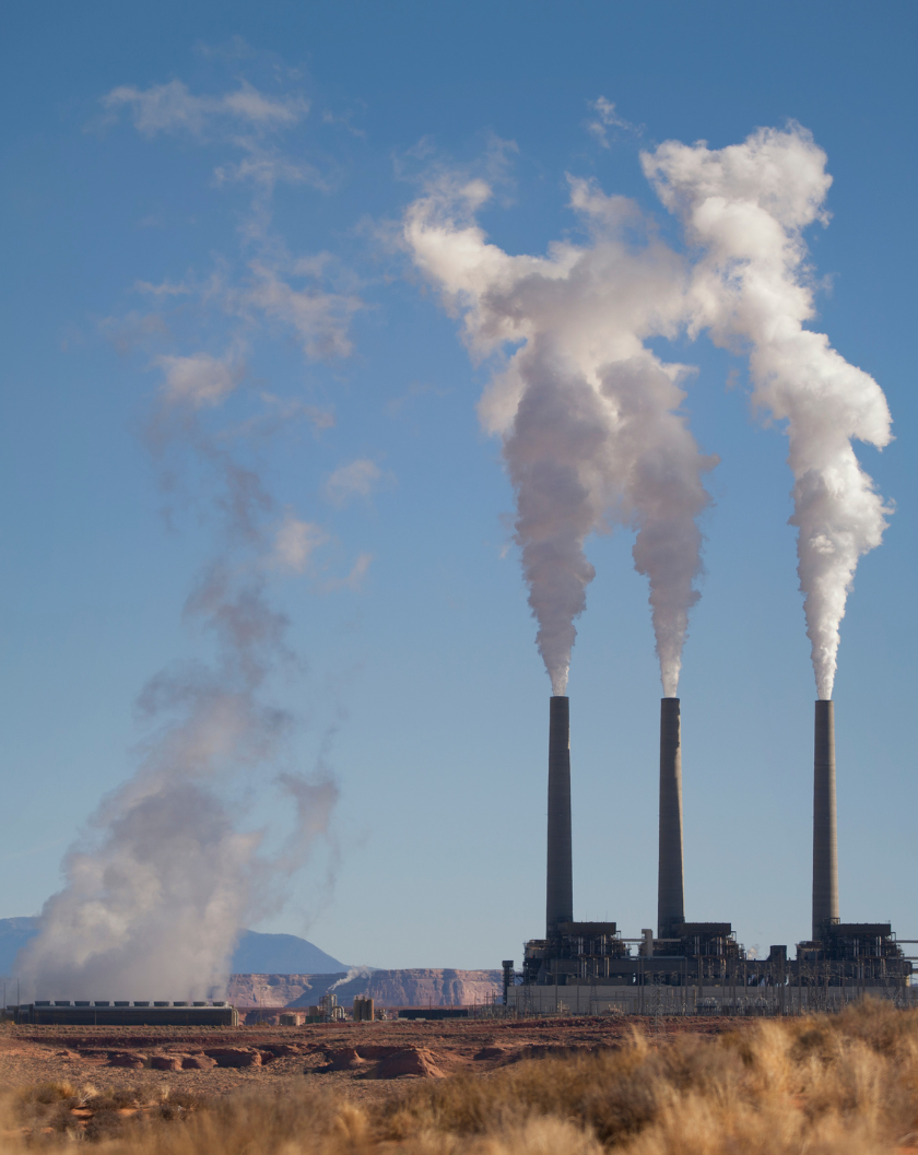 Industrial smoke stacks against a bright blue sky