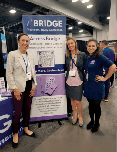 Access Bridge employees smiling by an informational banner