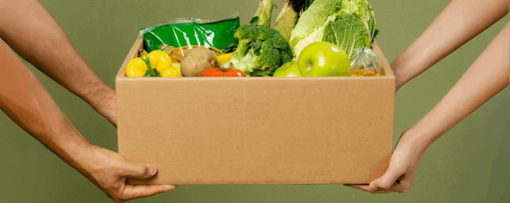 two people holding a box of healthy produce