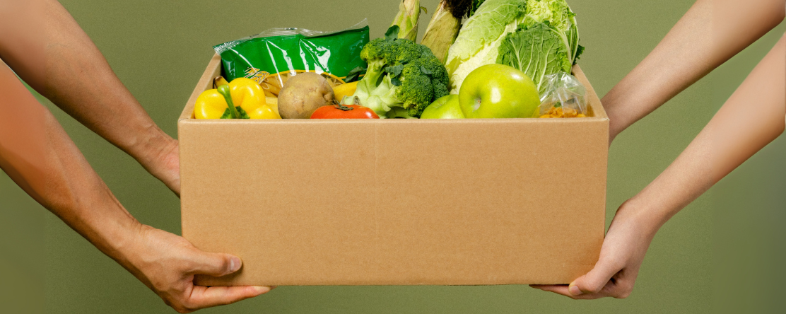 two people holding a box of healthy produce