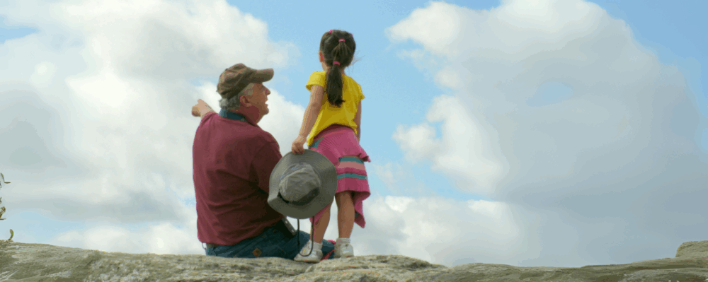 grandfather and granddaughter outside near cliff