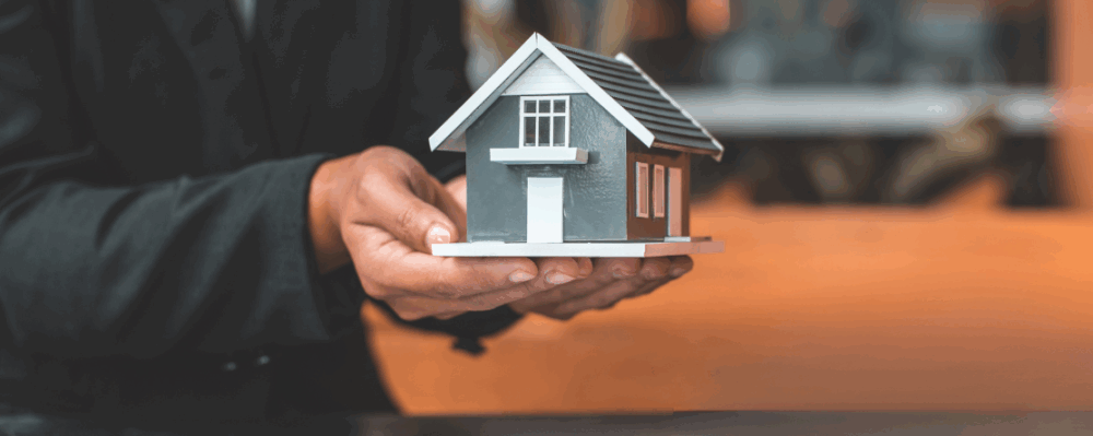 person holding tiny model of a house