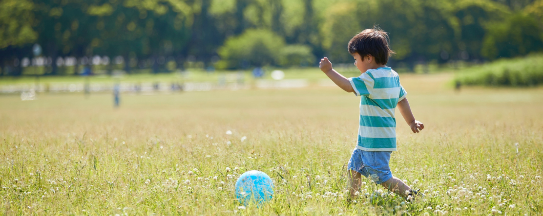 child playing with ball in field of grass
